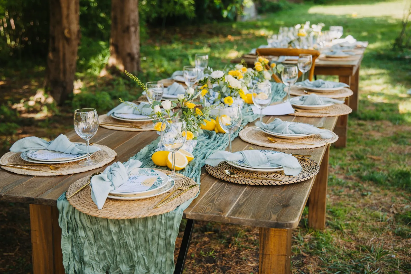 A long wooden table set for lunch in a garden