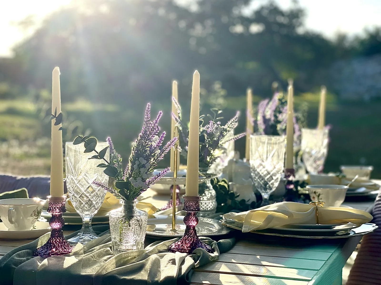 A table styled with candles, crystal and lavender, set outdoors
